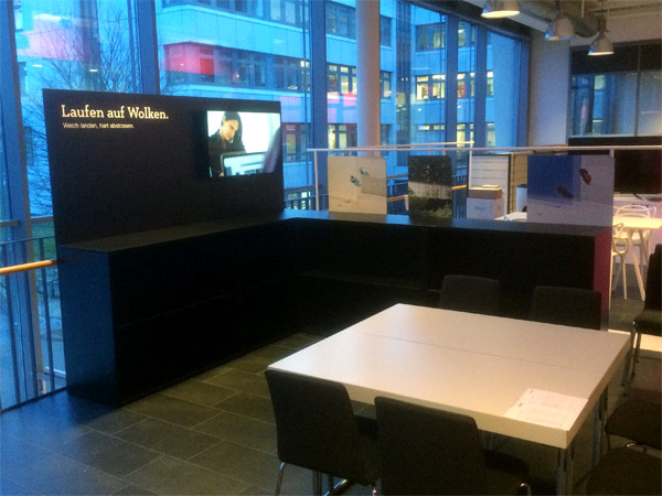 kleiner Messestand mit Regalen, Prsentern und schrgem Podest