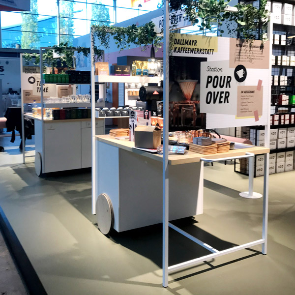 Messestand Kaffeewerkstatt, Stahlregale, Werkstattwagen, Klicklinoleum, geflieste Theke, Durchreiche, verputzte Kabine, Fenster, Anlehnhocker, Beistelltische