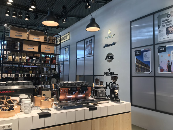 Messestand Kaffeewerkstatt, Stahlregale, Werkstattwagen, Klicklinoleum, geflieste Theke, Durchreiche, verputzte Kabine, Fenster, Anlehnhocker, Beistelltische